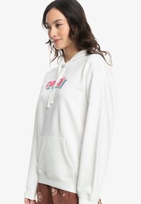 Witte hoodie met een kleurrijk "roxy" logo, trekkoord capuchon, voorzak en geribbelde manchetten. Zacht materiaal met een losse pasvorm.