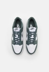 Nike sneakers with a white leather upper and green accents, featuring perforations, lace-up design, and padded collar for comfort.