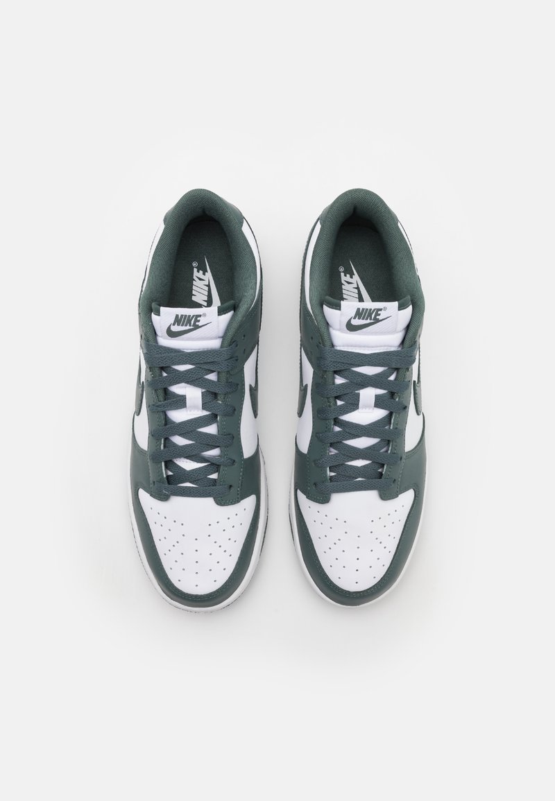 Nike sneakers met een bovenwerk van wit leer en groene accenten, met perforaties, vetersluiting en een gevoerde kraag voor comfort.
