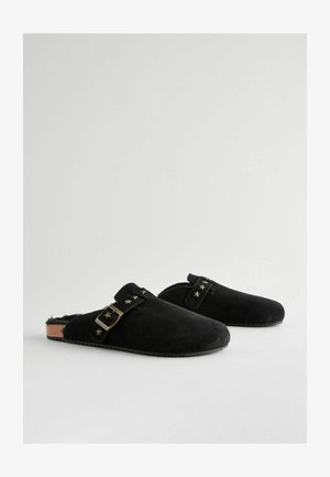 Čierne semišové dreváky s korkovou podrážkou, so strapcom s hviezdičkovými akcentmi a mosadznou sponou. Hladký povrch a uzavretý dizajn na päte.