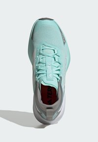 Jasnoniebieski but sportowy z teksturowaną siateczkową cholewką, szarymi akcentami, wzmocnionym noskiem i wyściełanym kołnierzem; posiada sznurowadła i amortyzowaną podeszwę.