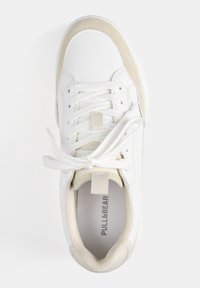 Baskets blanches avec dessus synthétique lisse et accents beige. Comprend des lacets plats, un col rembourré et une semelle intérieure texturée avec logo.