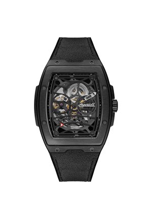 Montre automatique squelettée noire avec un boîtier rectangulaire, un bracelet en cuir et des mécanismes internes visibles. Détail triangulaire rouge notable.