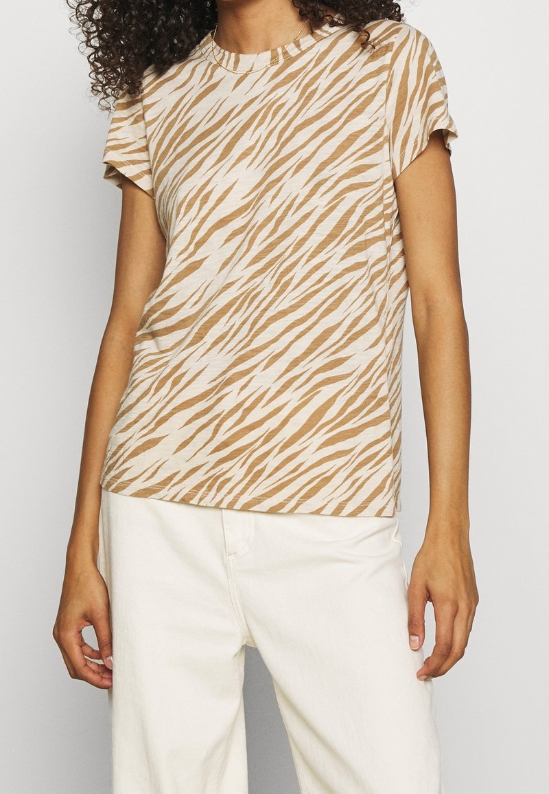 Beige t-shirt med ett tigerrandigt mönster i bruna nyanser. Den har korta ärmar, rund halsringning och ett mjukt, lätt tyg.