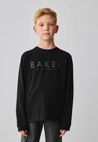Czarny t-shirt z długim rękawem z napisem "BAKER" wydrukowanym z przodu w ciemnoszarym kolorze. Materiał wydaje się miękki, a krój jest luźny z zaokrąglonym dekoltem.