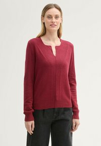 Burgundy knit sweater featuring a round neckline, long sleeves, and a subtle V-shaped seam detail at the front. Soft texture with ribbed cuffs.