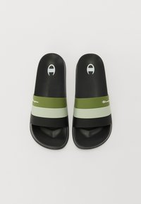 Sandalele negre cu talpă plată au trei dungi orizontale în verde închis, verde deschis și negru; talpă texturată cu accente ale logo-ului.