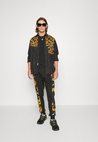 Versace Jeans Couture CHAIN - Trainingsbroek - black/gold