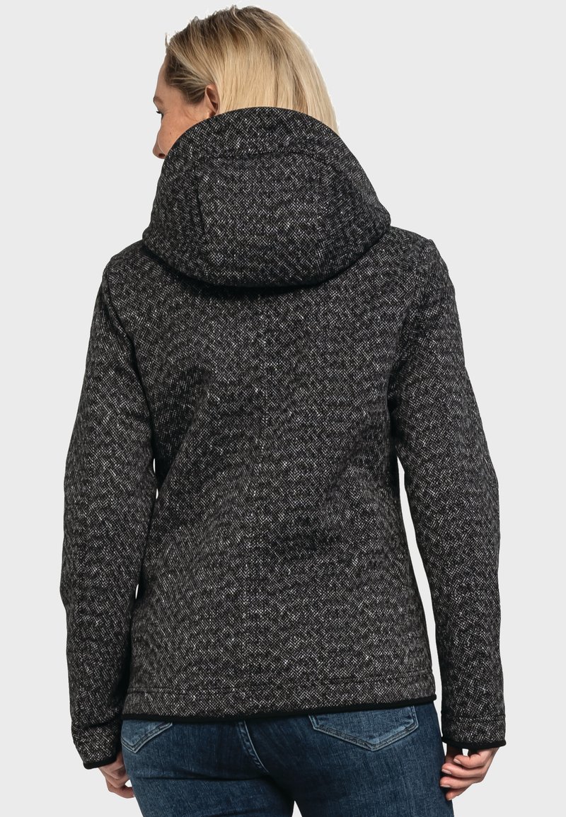 Giacca grigia scura a motivi con cappuccio, tessuto testurizzato e bordo nero solido all'orlo e ai polsini. Indossata con jeans blu.