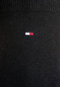 Sort besætningesok i ribbet stof med et lille logo i rød, hvid og blå broderet på siden. Blød tekstur.