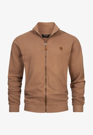 Giacca marrone a coste con zip e collo alto, maniche lunghe e un piccolo logo circolare sul petto.