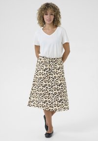Suknja midi duljine s leopard uzorkom, elastičnim pojasom i detaljem na vezanje; u kombinaciji s jednostavnom bijelom V-izrez majicom i crnim balerinkama.