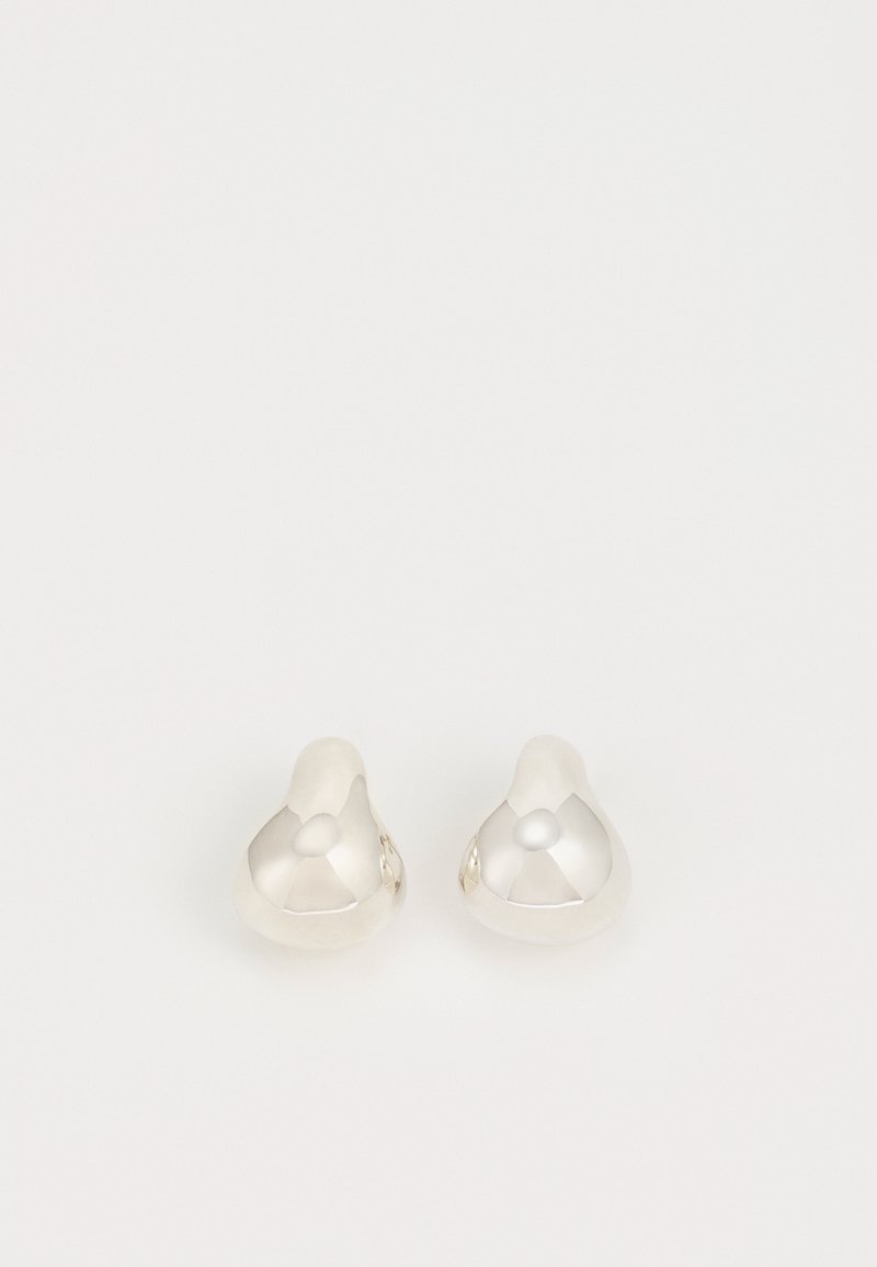 Orecchini in argento con una forma organica e arrotondata, con superficie lucida che riflette la luce e mostra una texture liscia.