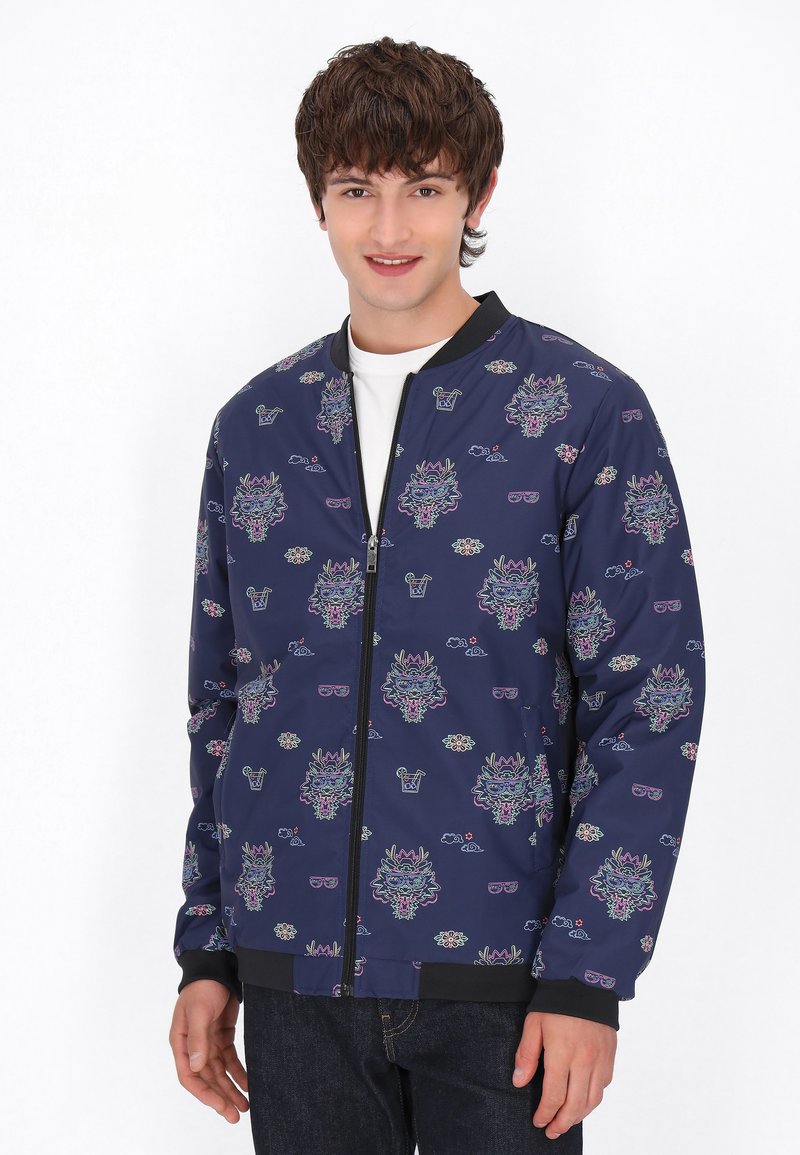 Giacca da bombardiere navy con grafiche floreali e animali colorate, polsini a coste e chiusura frontale con zip. Realizzata in tessuto leggero.