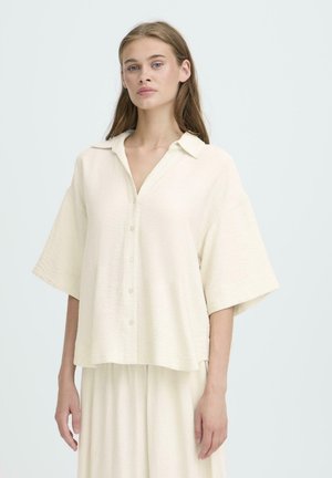 Kremowa koszula z guzikami, z kołnierzykiem i luźnymi, krótkimi rękawami. Teksturowana tkanina o delikatnym połysku. Dobierz do niej pasujące kremowe spodnie.