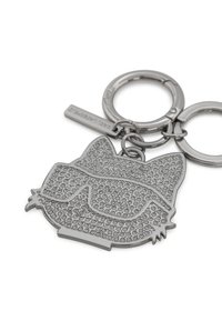 Porte-clé en argent en forme de visage de chat, avec une surface texturée ornée de petits strass et de lunettes de soleil surdimensionnées.