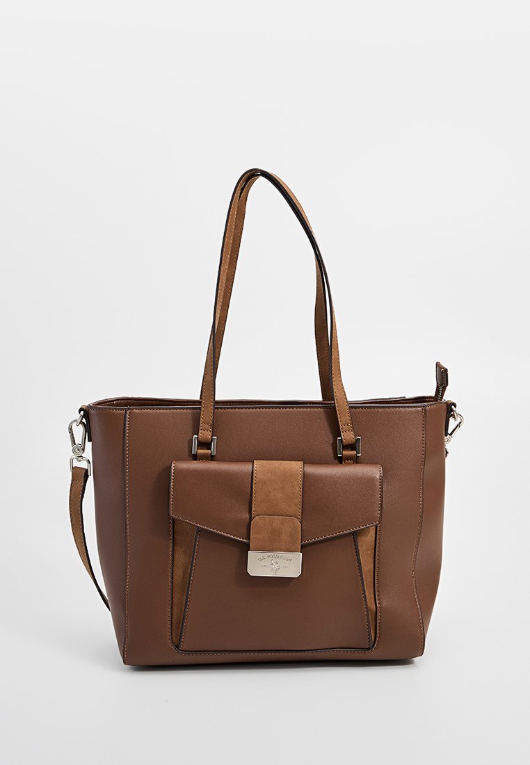 Braune Lederhandtasche mit Vordertasche, Klappenverschluss, metallischem Verschluss, doppelten Schulterriemen und abnehmbarem Seitengurt auf einem einfarbigen Hintergrund.