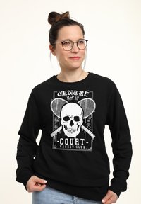 Černá mikina s grafickým potiskem lebky s tenisovými raketami a textem: "CENTRE COURT RACKET CLUB." Hladké manžety a výstřih.