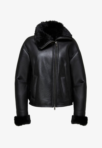 Giubbotto in pelle nera con colletto e polsini in pelliccia morbida, chiusura con zip e due tasche frontali. La finitura ha una texture liscia.