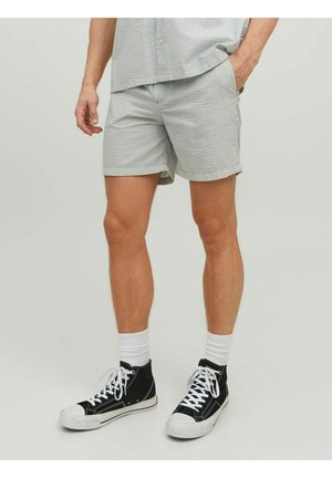 Man wearing light gray checkered shorts, matching shirt, white crew socks, and black high-top sneakers against plain background.