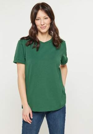 Grøn kortærmet t-shirt med rund halsudskæring og afslappet pasform, lavet af blødt stof. Sammen med blå denim jeans.