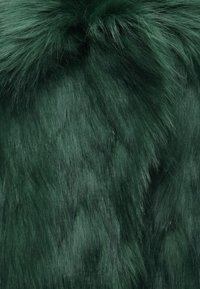 Πράσινο ύφασμα από συνθετική γούνα με μαλακή υφή και αποχρώσεις που ποικίλλουν. Η τρίχα είναι μακριά και πυκνή, δημιουργώντας μια πολυτελή εμφάνιση.