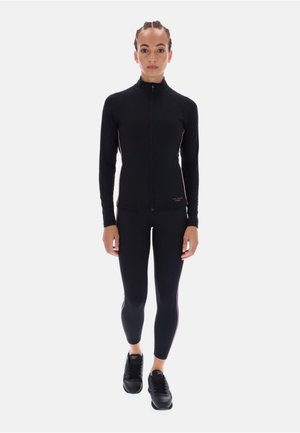 Sort atletisk jakke med høj krave, fuld lynlås og lange ærmer, kombineret med sorte leggings med en slim fit og diskrete lyserøde accenter.