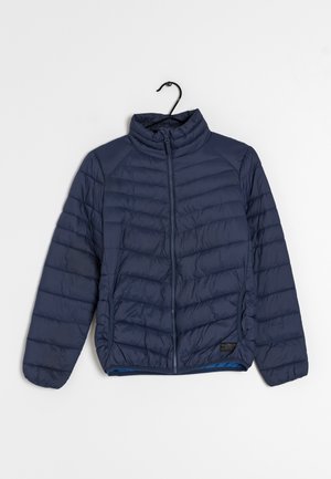 Chaqueta acolchada azul marino con cremallera completa en la parte delantera y cuello alto, colgada en una percha negra sobre un fondo blanco.