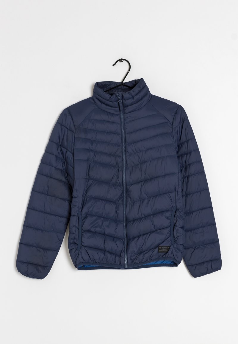 Veste matelassée bleu marine avec fermeture éclair intégrale à l'avant et col montant, suspendue à un cintre noir sur fond blanc.