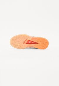 Shoe outsole in light orange with a textured herringbone pattern and a molded heel support, featuring a transparent accent window.