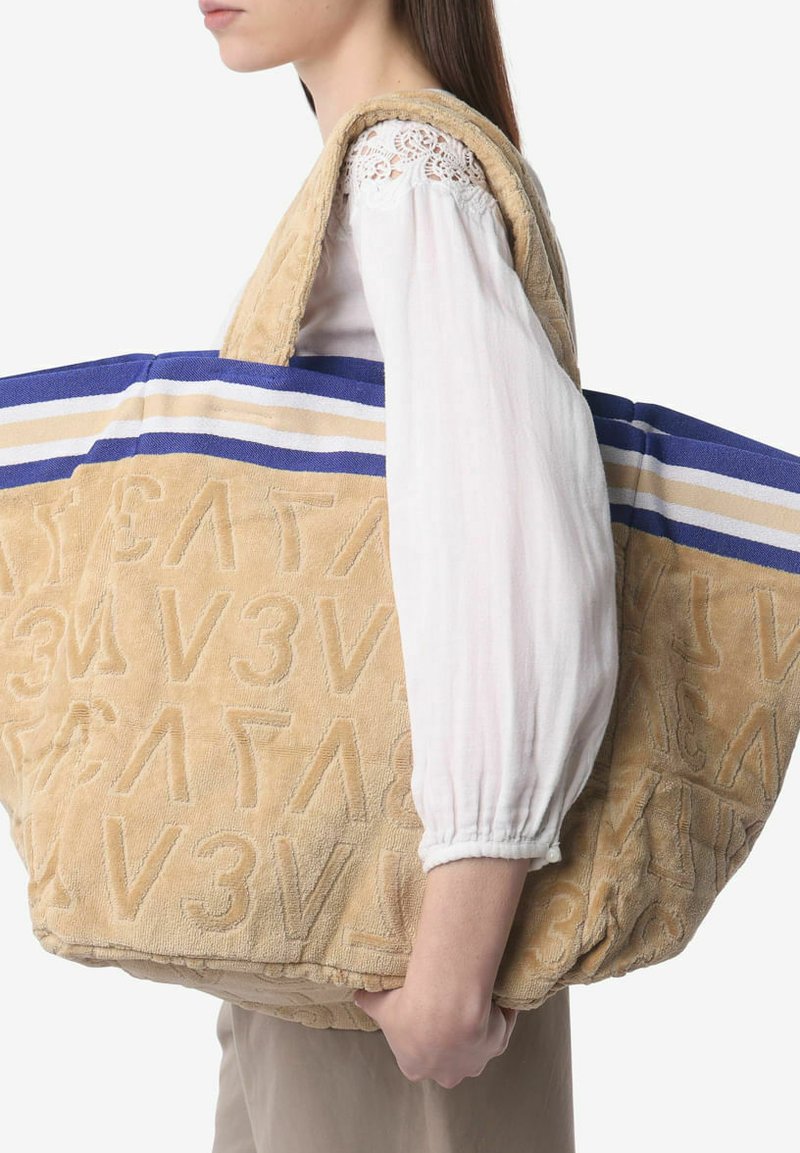 Beige badstof stoffen totebag met geperste letters, blauwe en crèmekleurige gestreepte accenten, grote maat, dikke schouderbanden en een gestructureerd oppervlak.