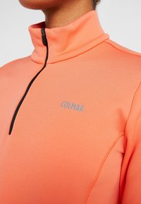 Fleece half-zip trui in fel koraal met een hoge kraag. Voorzien van een contrasterende zwarte rits en het "COLMAR" logo in het grijs op de borst.