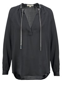 Blouse noire à manches longues avec un col en V, des accents de chaîne argentée au niveau du col, et un ourlet légèrement incurvé. Texture du tissu douce et lisse.