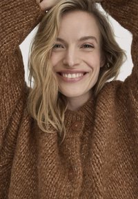 Brauner gestrickter Pullover mit einem strukturierten Muster, runder Ausschnitt und zwei Holzknöpfen vorne. Weicher, kuscheliger Look.