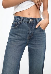 Ljust blå denimjeans med en avslappnad passform, som har knäppning med knapp, fem fickor och kontrasterande sömmar.
