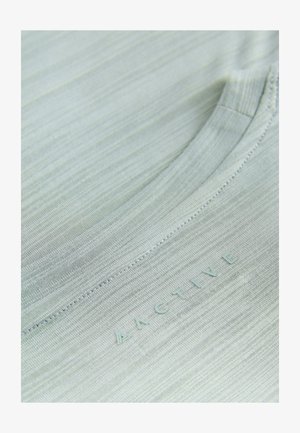 Gaiši zaļa sporta krekla augšdaļa ar gludu, teksturētu virsmu. Ir apaļa kakla izgriezums un drukāta "ACTIVE" logo.