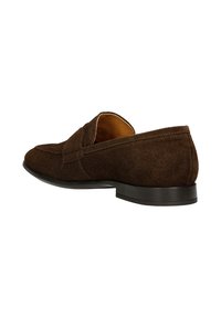 Mocassin homme en daim marron foncé avec semelle noire, présenté sous un léger angle, mettant en avant les détails latéraux et arrière.