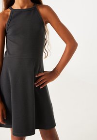 Geripptes, dunkelgraues ärmelloses Kleid mit tailliertem Oberteil und ausgestelltem Rock. Verfügt über einen Rundhalsausschnitt und feine Textur.