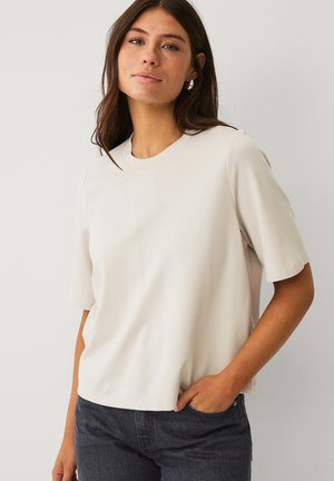 Lys beige kortærmet t-shirt med rund halsudskæring, lavet af glat stof, med en afslappet pasform og subtile stikninger.