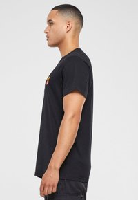 Un tricou negru cu mâneci scurte, guler rotund și un mic logo brodat pe piept. Fabricat din bumbac, cu un design ajustat.