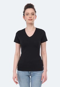 T-shirt nera a maniche corte con scollo a V, realizzata in cotone morbido. Design aderente con una texture liscia, indossata con jeans blu. Stile semplice e versatile.