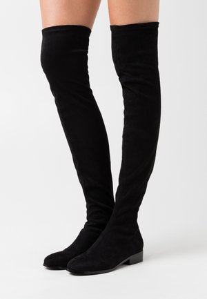 Bottes noires en daim au-dessus du genou avec une semelle plate et un bout arrondi, présentant une texture lisse et des coutures discrètes le long des seams.