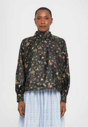 Blusa nera floreale con maniche a sbuffo lunghe, colletto alto e motivo floreale multicolore; tessuto in satin. Indossata su una gonna plissettata azzurro chiaro.