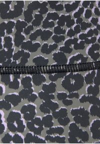 Löwenmusterstoff mit einer strukturierten Oberfläche, in Schwarz- und Grautönen, mit schwarzen Fäden entlang der Naht genäht.