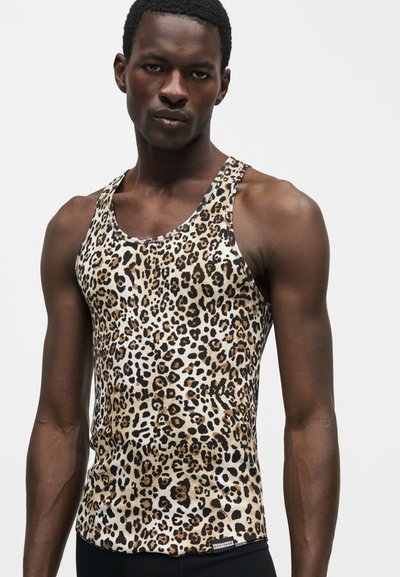 Κοντό top στενής εφαρμογής χωρίς μανίκια με καφέ, μαύρο και μπεζ λεοπάρ σχέδιο, φορεμένο από έναν άνδρα που στέκεται μπροστά σε απλό ανοιχτόχρωμο φόντο.
