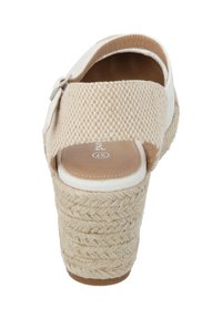Beige espadrille wedge sandaal met een gevlochten jute zool, een strakke bovenkant van stof en een gesp sluiting. Ontwerp met open achterkant.
