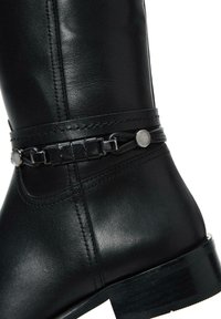 Stivale in pelle nera alta fino al ginocchio con una texture liscia, cinturino decorativo con accenti in metallo e un tacco robusto e curvato.