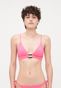 Roze bikini top met driehoekige cups, verstelbare bandjes en zwarte hardware-details in het midden met het merklogo. Soepele textuur.