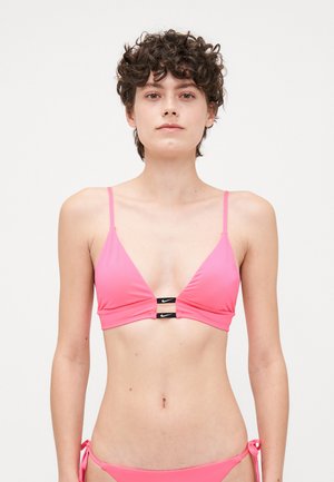 Haut de bikini rose avec des bonnets triangulaires, des bretelles réglables et un détail en métal noir au centre arborant le logo de la marque. Texture lisse.