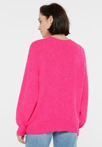 Helles pinkes, übergroßes Sweatshirt mit weicher Textur, gerippten Bündchen und Saum. Mit abgesenkten Schultern und Rundhalsausschnitt, für eine lässige Passform gestaltet.
